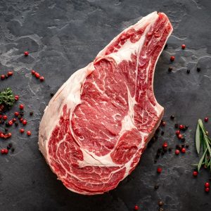 Raw,Cowboy,Steak,With,Seasonings,On,Stone,Background,,Prime,Rib